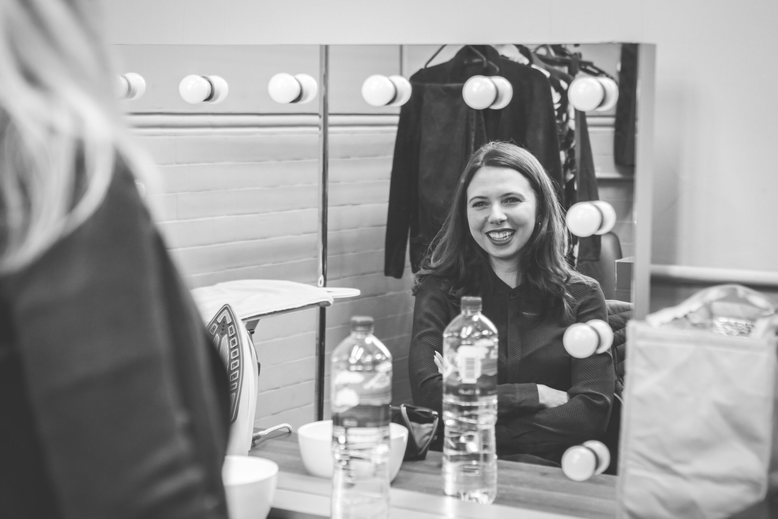 Black and white photo of a female actress looking into a dressing room mirror
